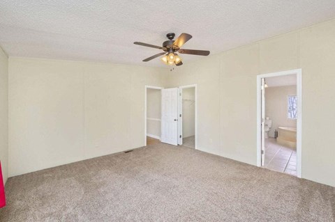 an empty living room with a ceiling fan