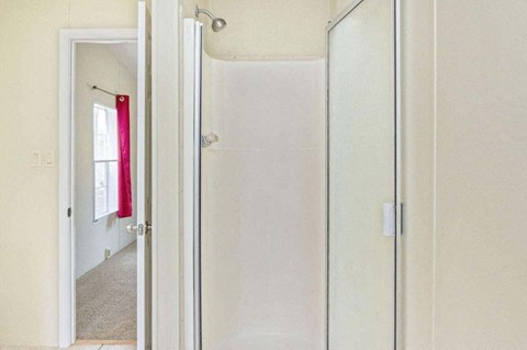 a white bathroom with a shower and a door