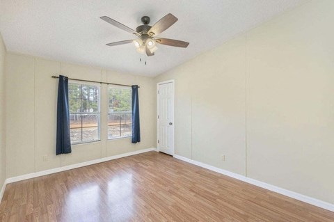 an empty living room with a ceiling fan and a window