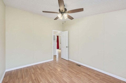 an empty living room with a ceiling fan and wood floors