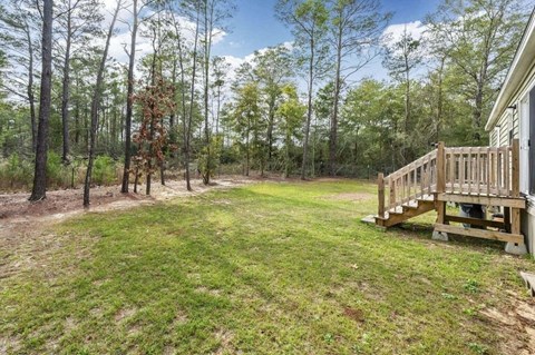 the backyard of a house with a wooden deck in the woods