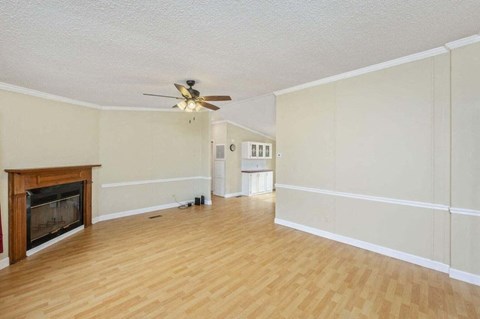 an empty living room with a fireplace and a ceiling fan