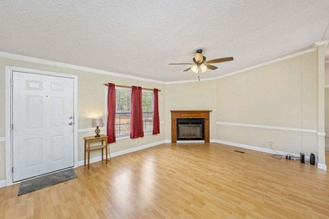 an empty living room with a fireplace and a ceiling fan