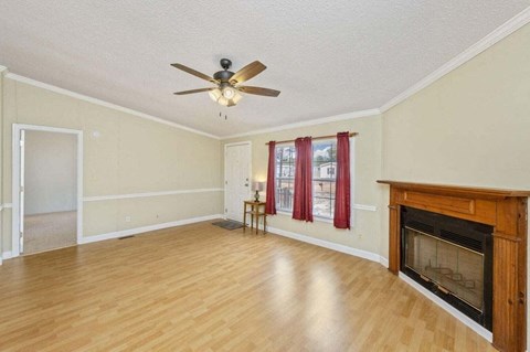 an empty living room with a fireplace and a ceiling fan