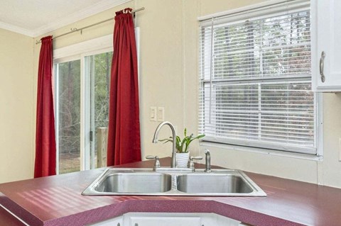 a kitchen with a sink and a window with red curtains