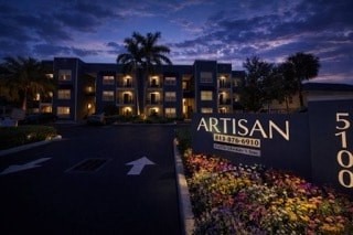 The Artisan hotel sign is lit up at night.