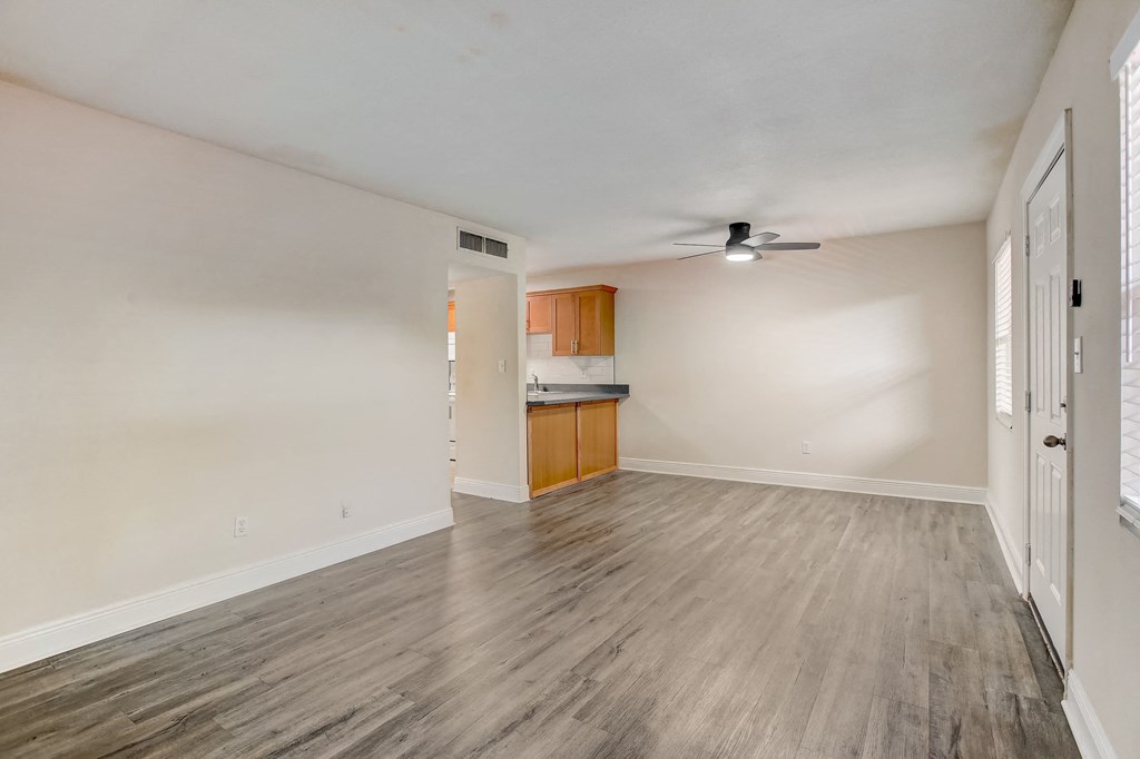 the living room and kitchen of an empty home with wood flooring