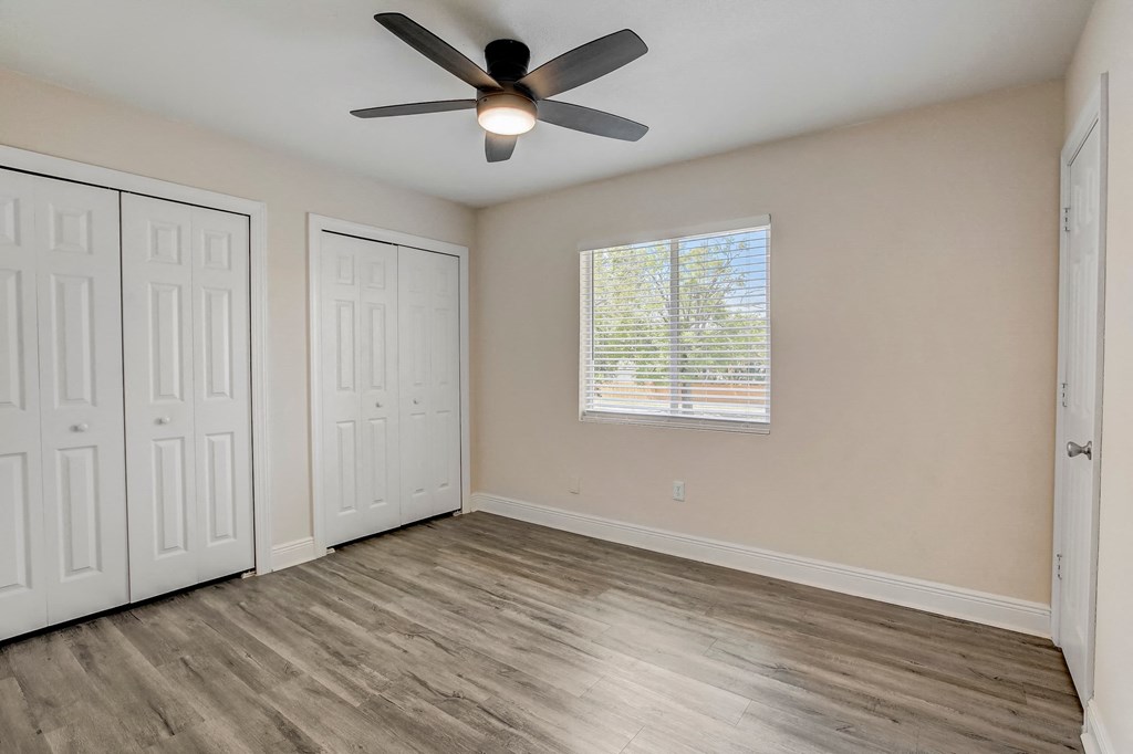 an empty living room with a ceiling fan and a window