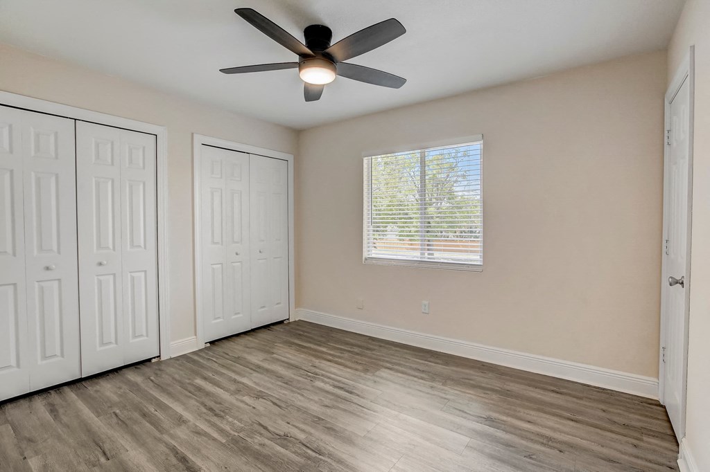 an empty bedroom with a ceiling fan and a window