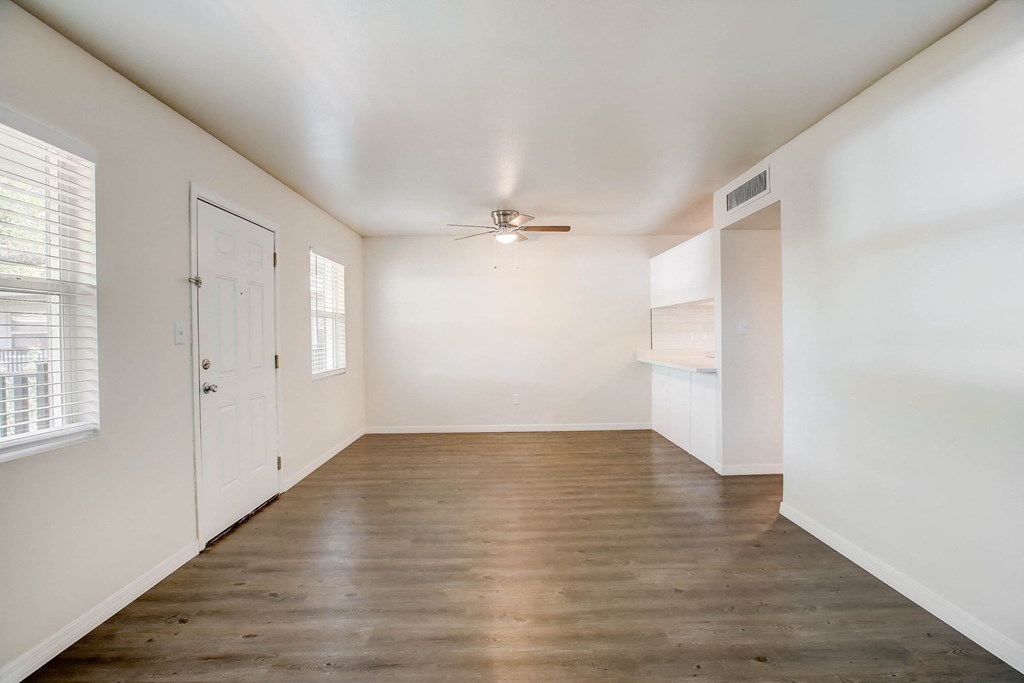 an empty living room with white walls and a ceiling fan