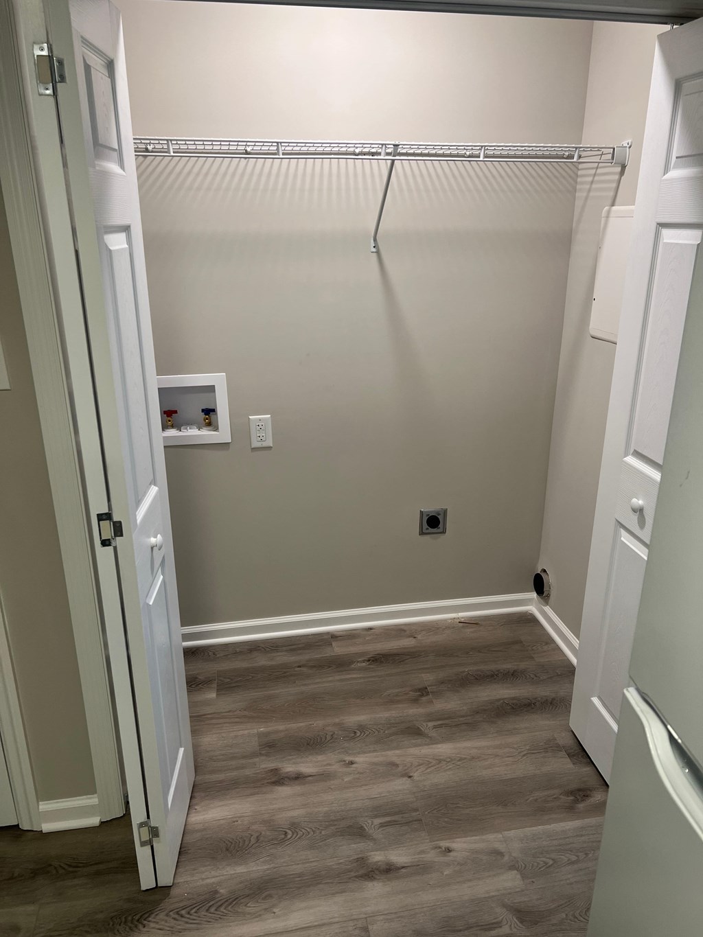 A walk-in closet with a white door and a grey floor.