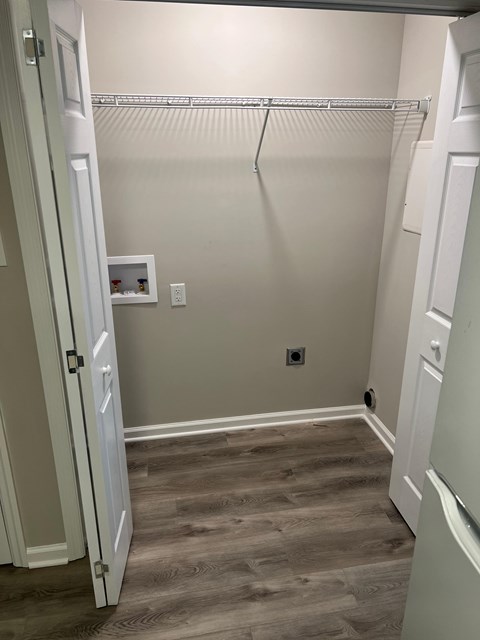 A walk-in closet with a white door and a grey floor.