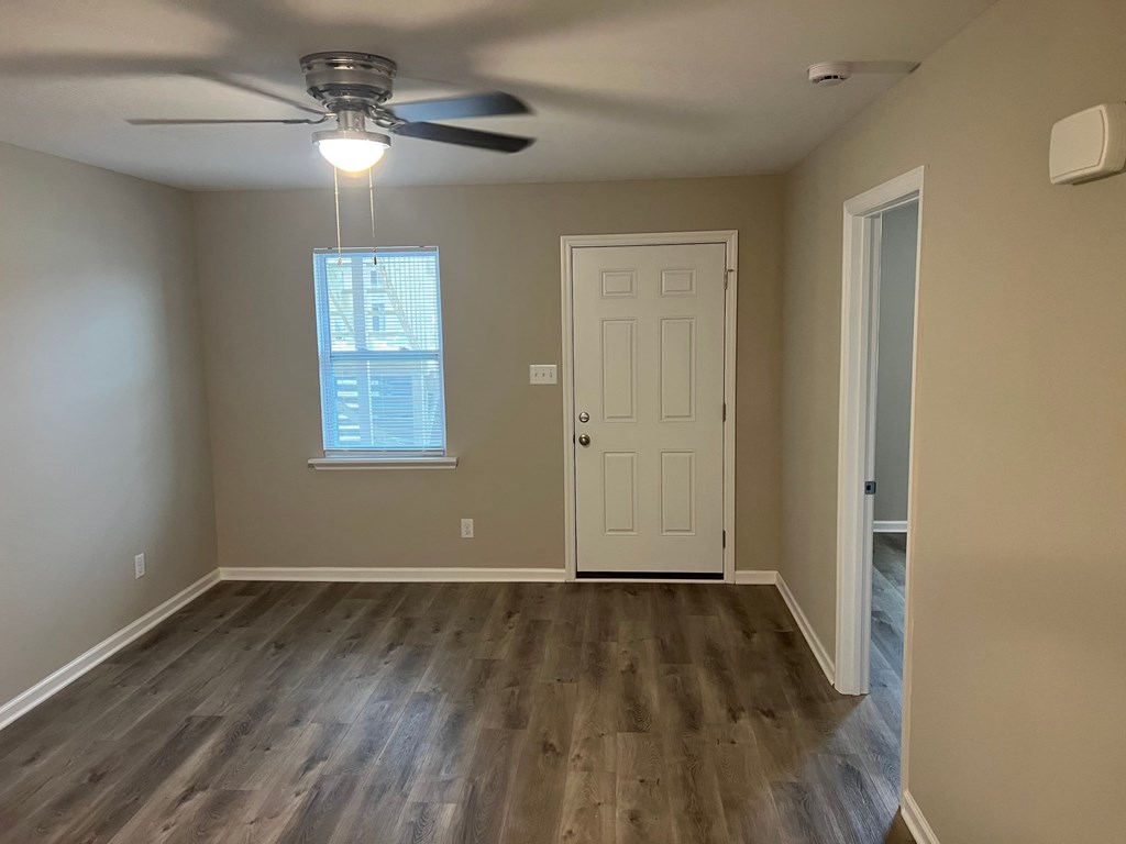 A room with a ceiling fan and a door.