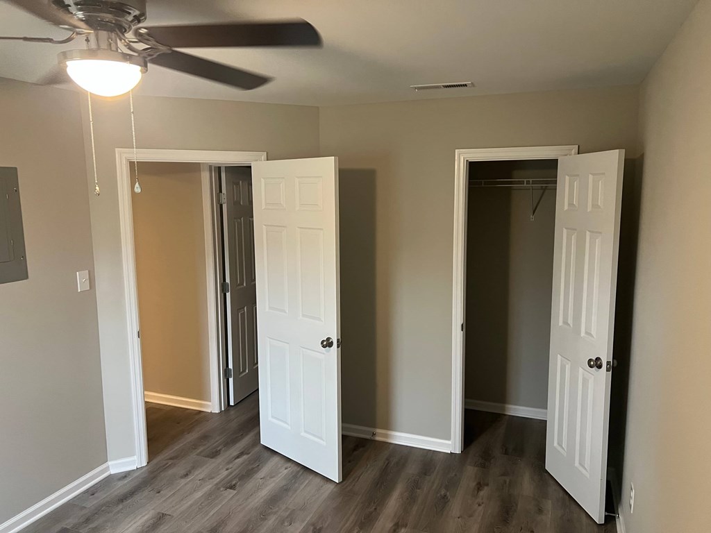 A room with a ceiling fan and three doors.