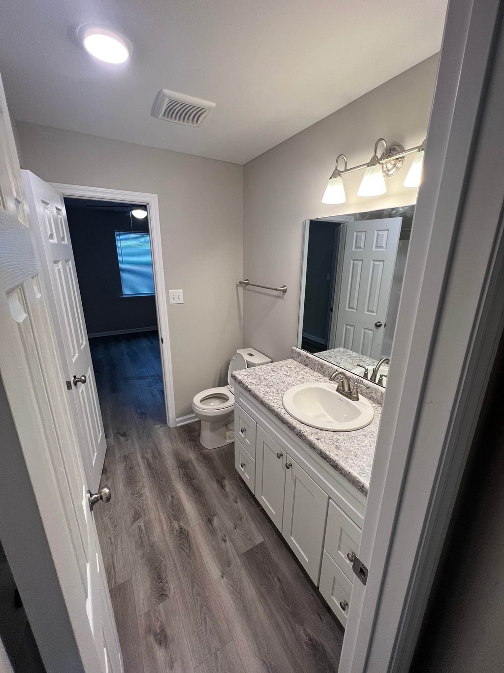 A bathroom with a toilet, sink, and mirror.