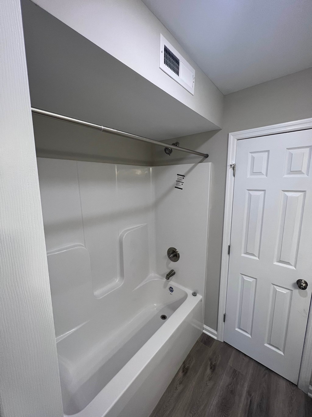 A white bathroom with a tub and a door.