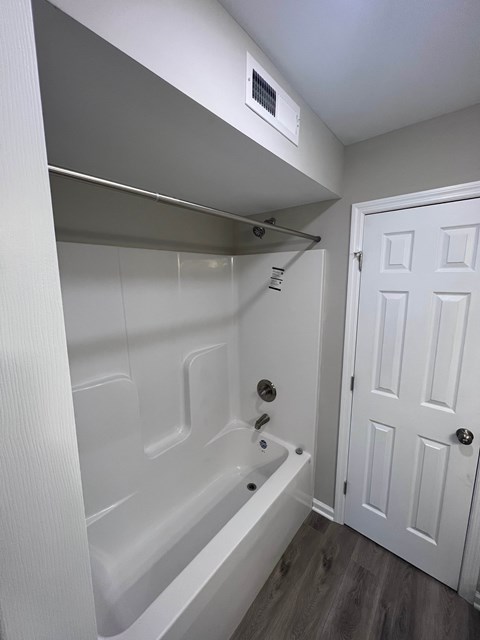 A white bathroom with a tub and a door.