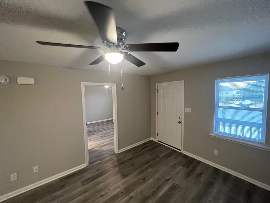 A room with a ceiling fan and a window with blinds.