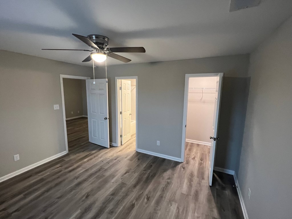 A room with a ceiling fan and wooden flooring.