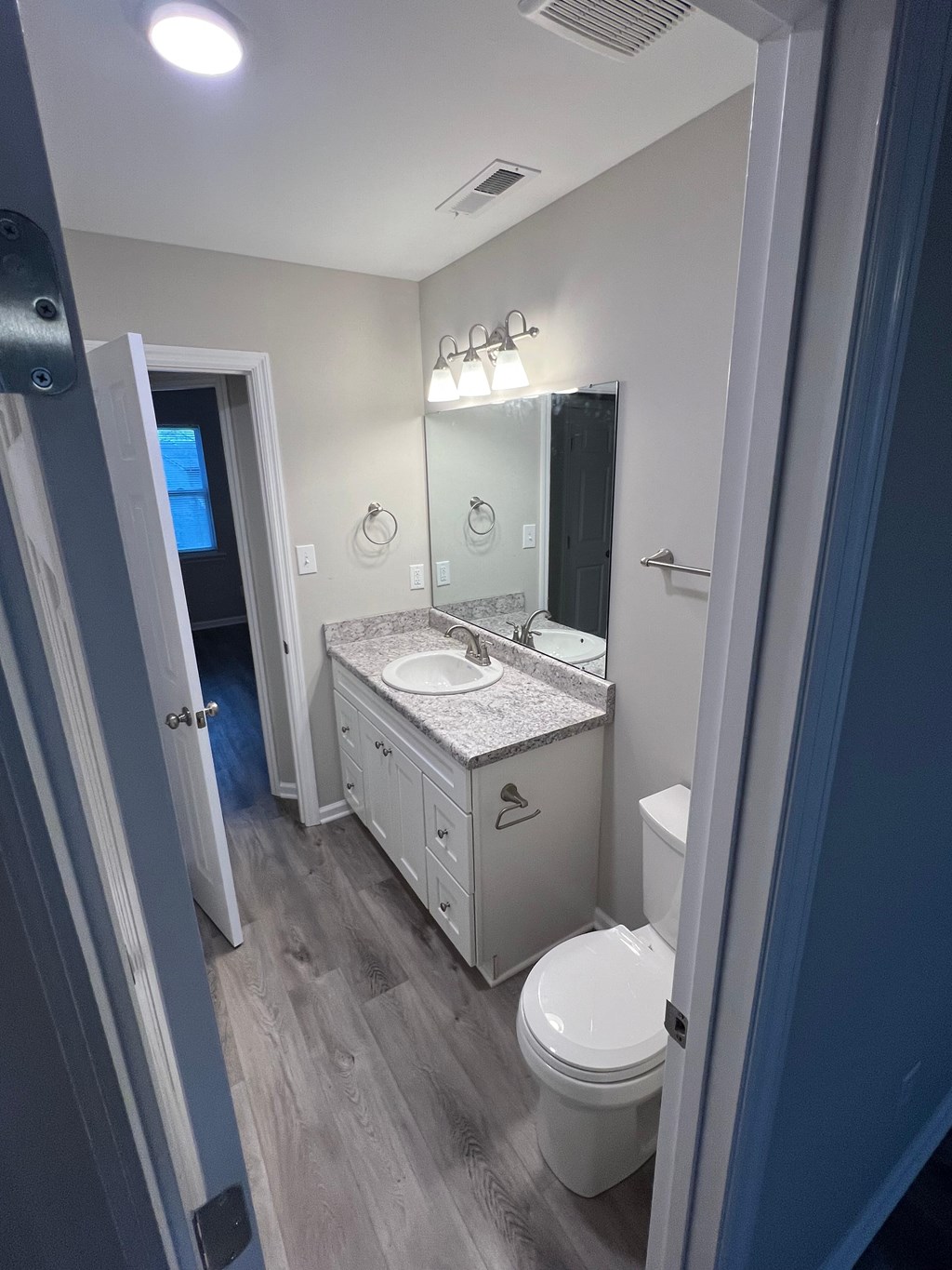 A bathroom with a toilet, sink, and mirror.