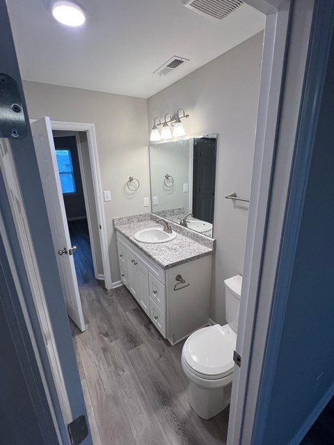 A bathroom with a toilet, sink, and mirror.