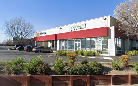 the front of a shopping center with cars parked in a parking lot