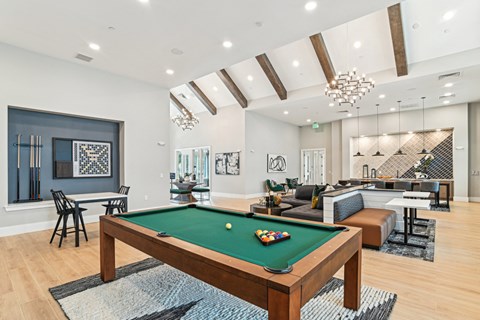 A pool table is in the middle of a room with a couch and chairs.
