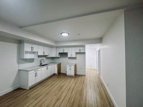 an empty kitchen with white cabinets and a wood floor