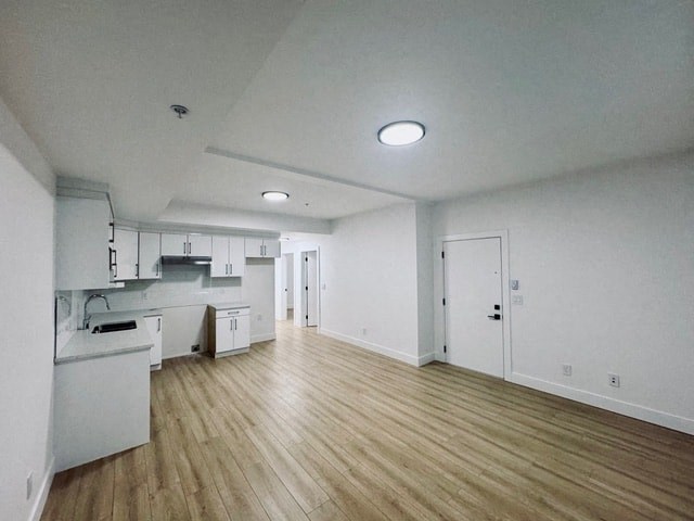 an empty living room and kitchen with wood floors