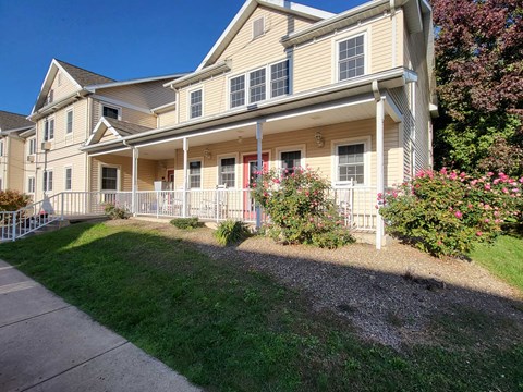 a large yellow house with a sidewalk in front of it
