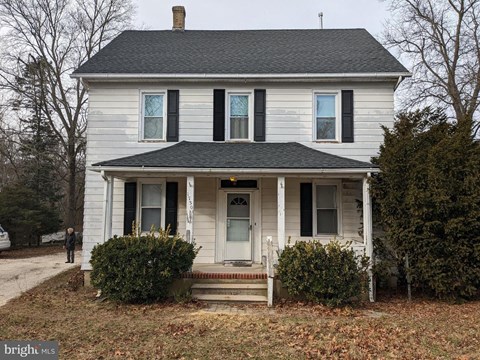 A white house with a black roof and a chimney.