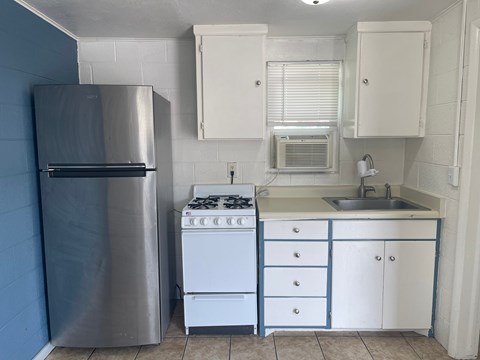 A kitchen with a stainless steel refrigerator, a white stove, and white cabinets.