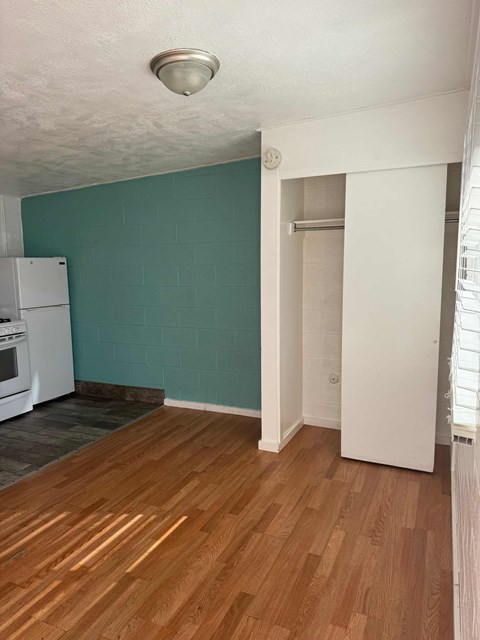 A kitchen with a white refrigerator and wooden floors.