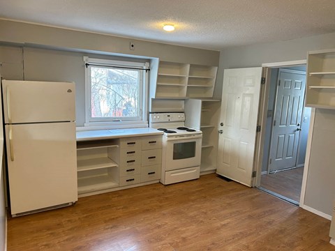 A kitchen with a white refrigerator, a window, and a white oven.