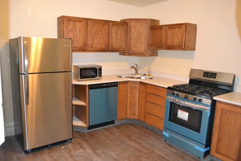 A kitchen with a refrigerator, microwave, oven, and sink.