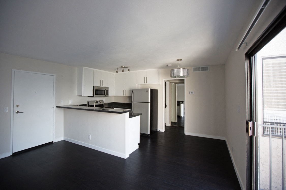 an empty kitchen with white cabinets and a black floor