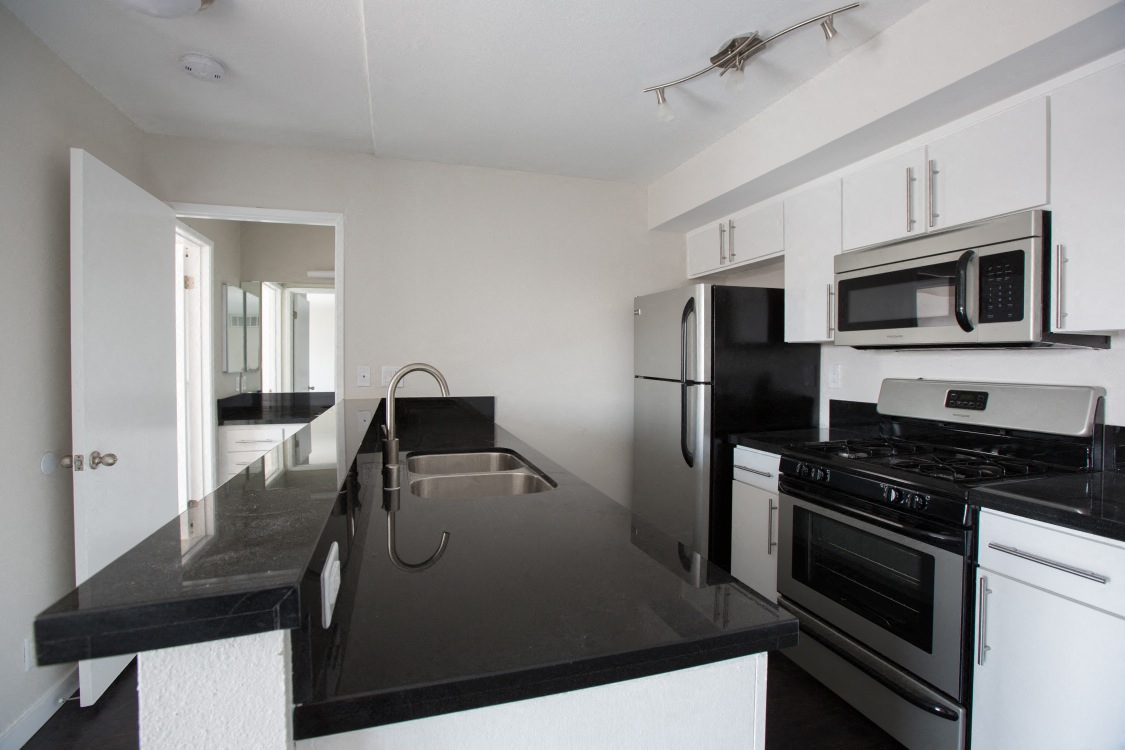 an empty kitchen with black counter tops and black appliances