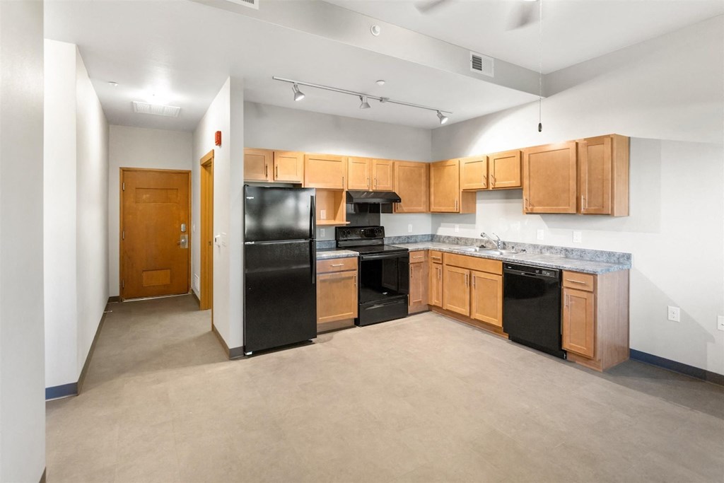 a spacious kitchen and living area with efficient appliances and wood cabinets