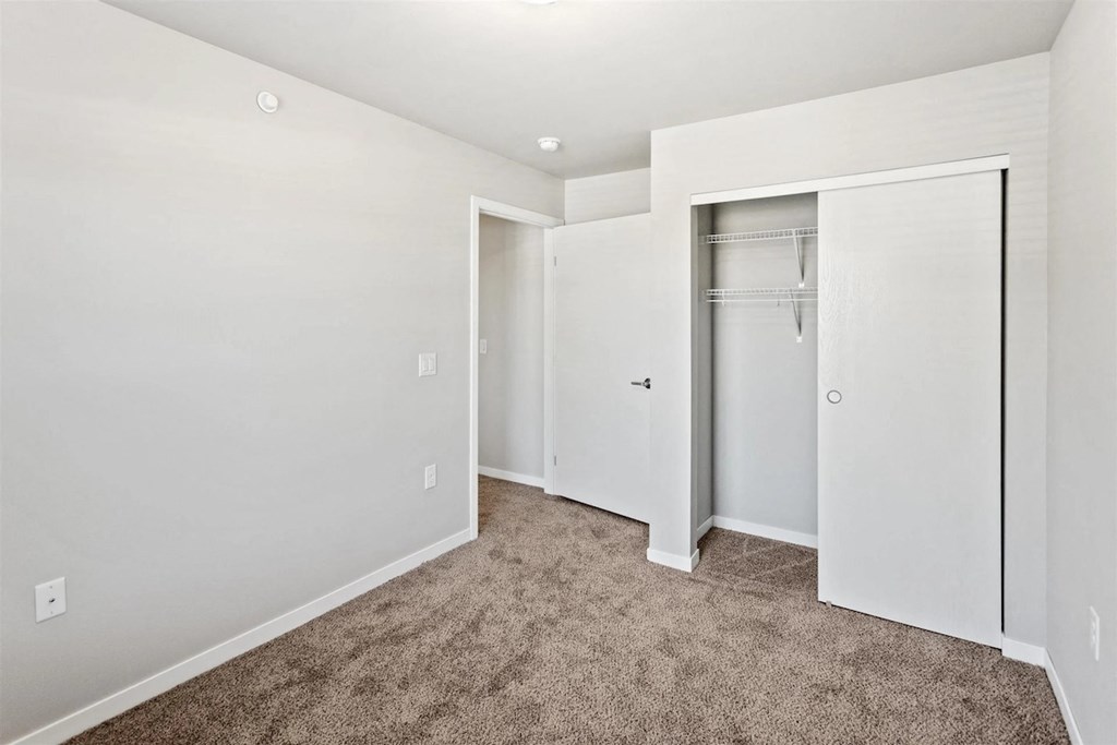 a bedroom with white walls, plush carpeting, and a closet at Muskego School
