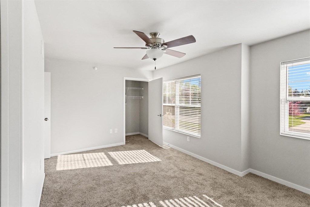 a spacious room with carpet, a ceiling fan, and ample natural light from large windows