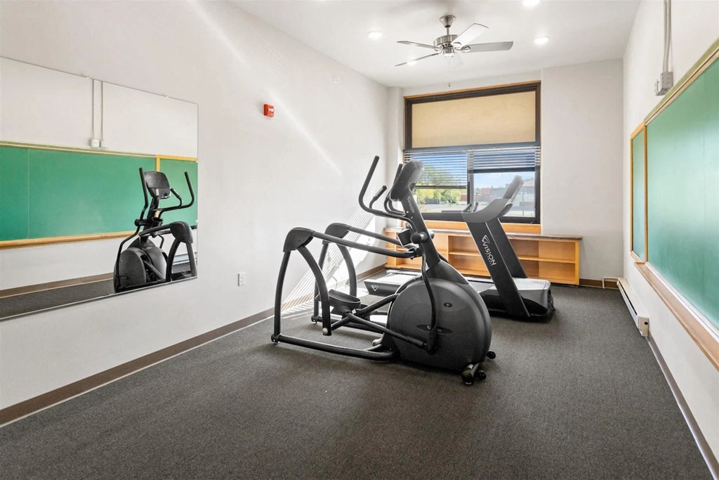 Muskego School's fitness center with cardio equipment, wall chalkboards, mirrors, and a ceiling fan