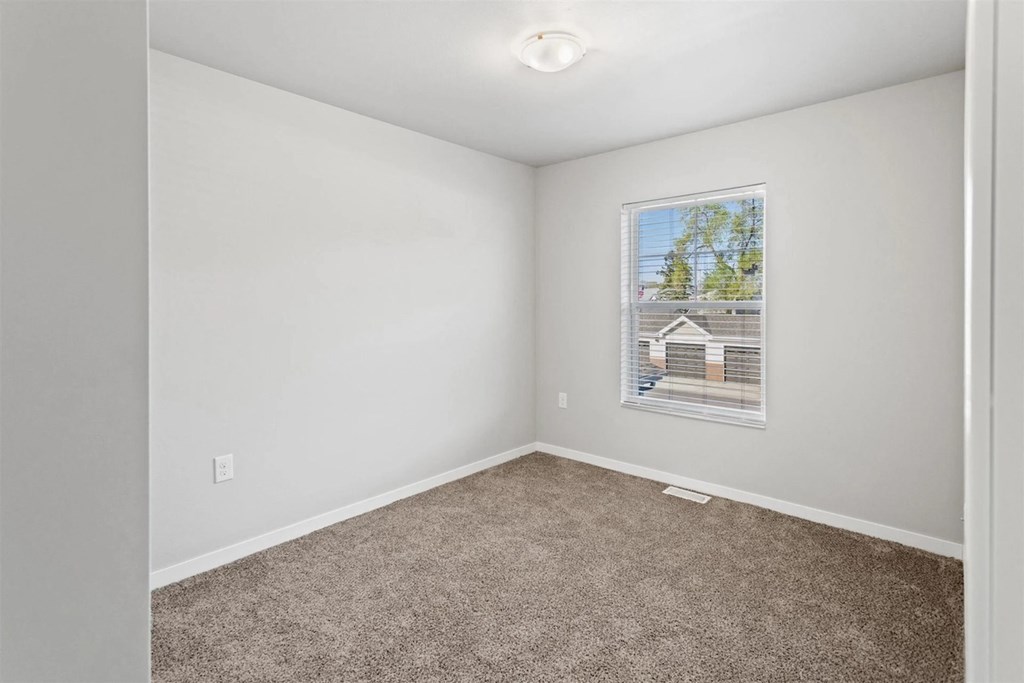 a large carpeted bedroom with overhead lighting and a window at Muskego School