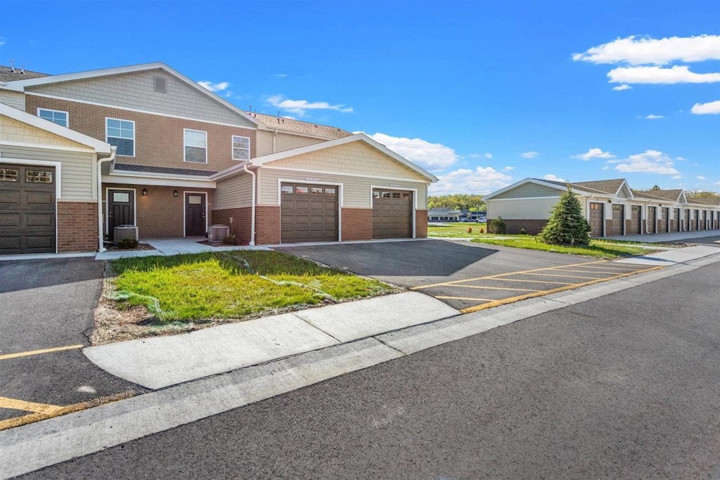 Brick and siding apartments with garages and driveways at Muskego School Apartments