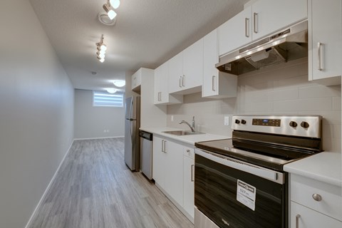an empty kitchen with white cabinets and stainless steel appliances and a stove