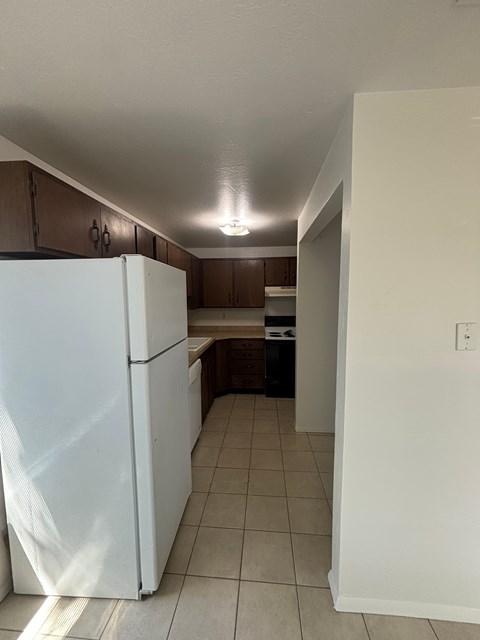 A white refrigerator in a kitchen with brown cabinets.