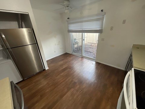 A kitchen with a refrigerator and a wooden floor.