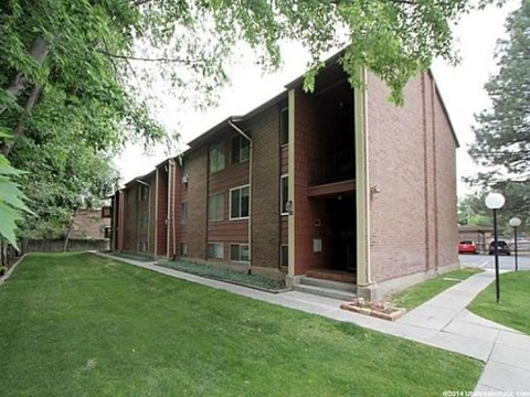 A building with a red brick exterior and a green lawn in front.