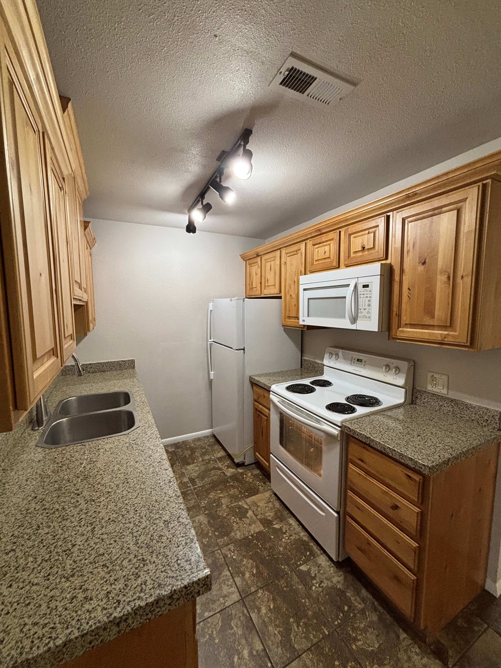 A kitchen with granite countertops and wooden cabinets.