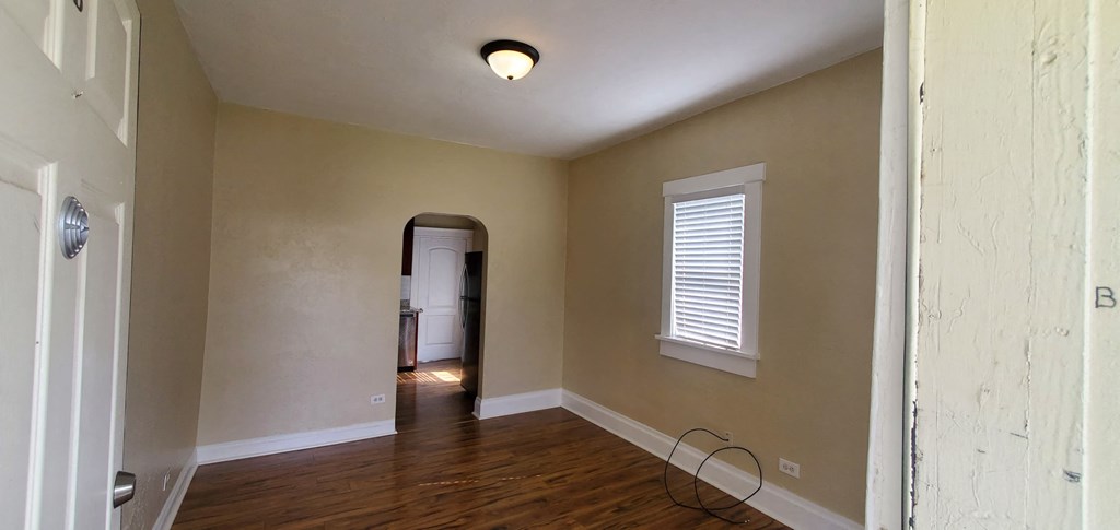 an empty living room with a window and a door to a hallway