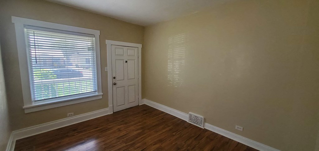 a bedroom with a door and a window and a wooden floor